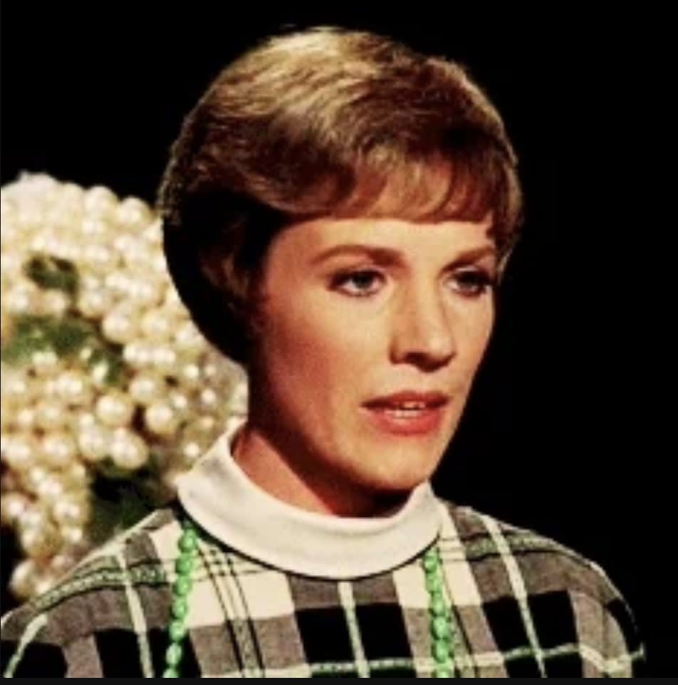 Julie Andrews in a checkered outfit with a floral background