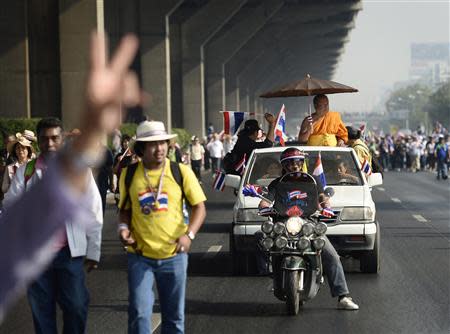 A monk (R) travels in a vehicle as he participates in an anti-government rally in Bangkok December 9, 2013. REUTERS/Dylan Martinez