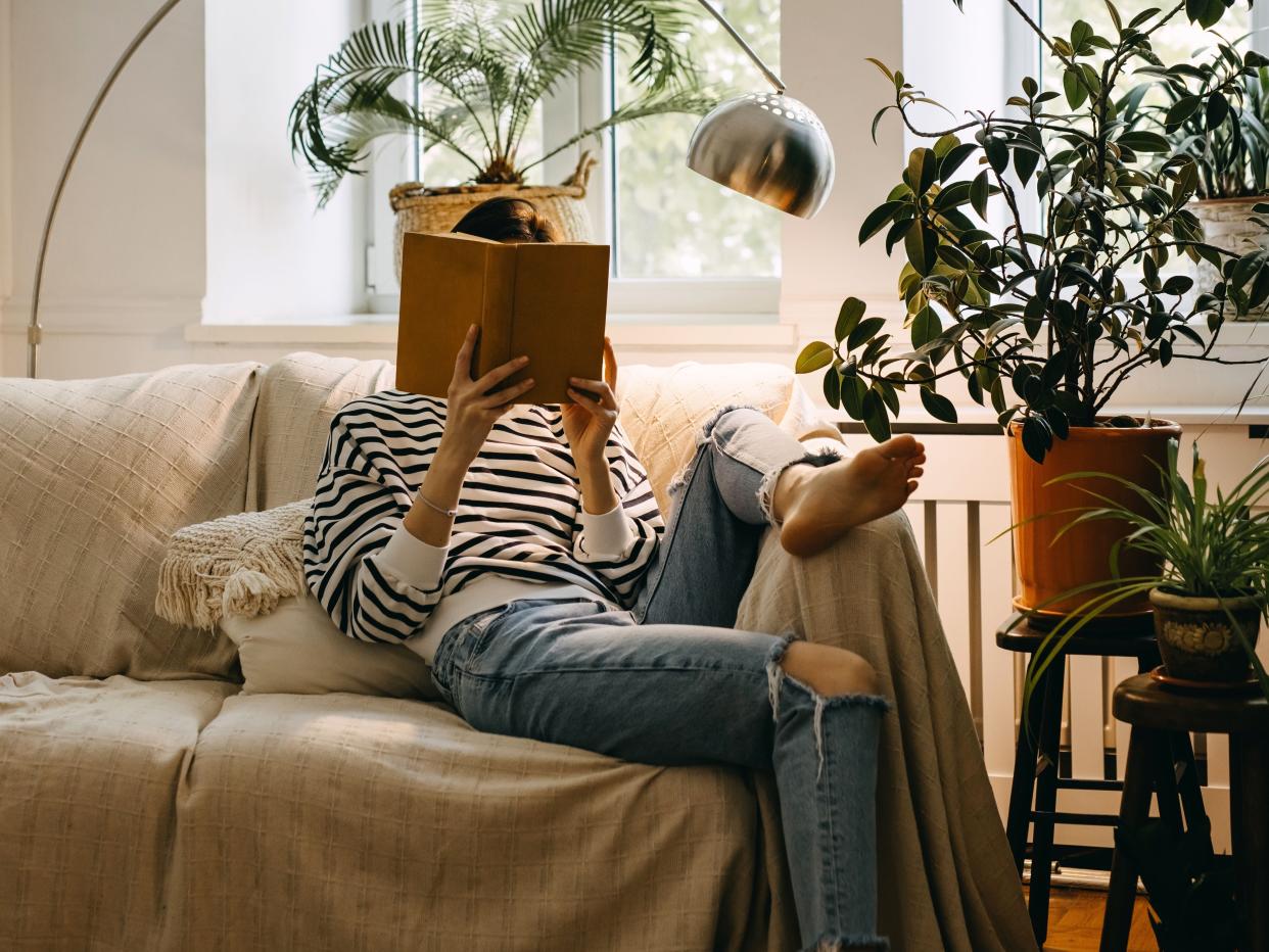 A girl sitting on a sofa and reading a book