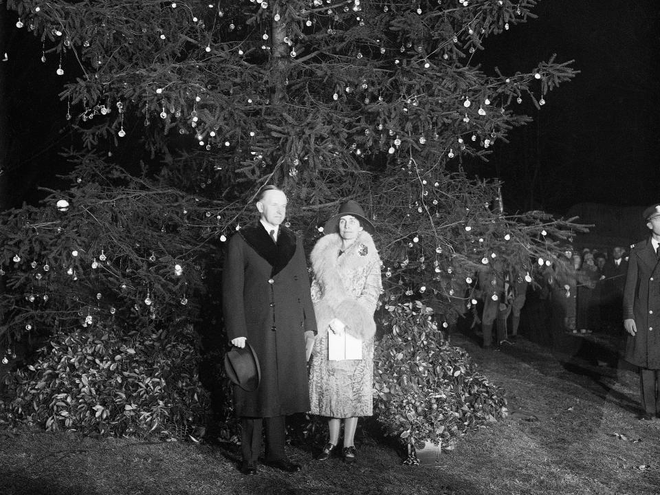 President Calvin Coolidge and first lady Grace Coolidge stand in front of the national Christmas tree.