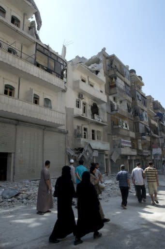 Syrians walk past buildings damaged by bombing by the Syrian regime forces in the northern Syrian city of Aleppo. Regime aircraft hammered insurgent bastions nationwide on Sunday as rebels said they now control most of the country and have moved their command centre from Turkey to "liberated areas" inside Syria