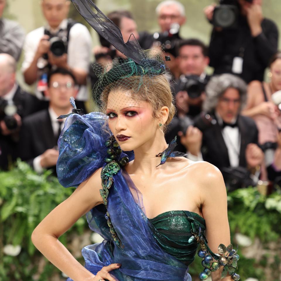 Zendaya in avant-garde blue gown with netted headpiece at event