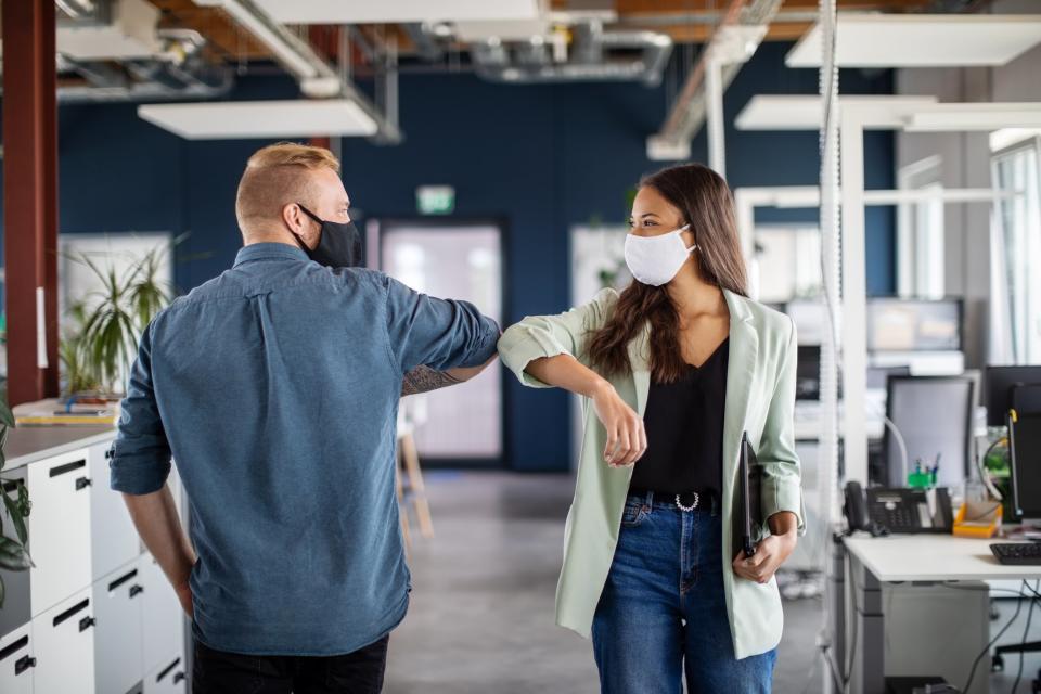 Two business colleagues greeting with elbow in office. Business people bump elbows in office for greeting during covid-19 pandemic.