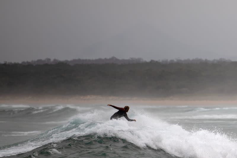 A surfer rides a wave in Bengello beach in Broulee