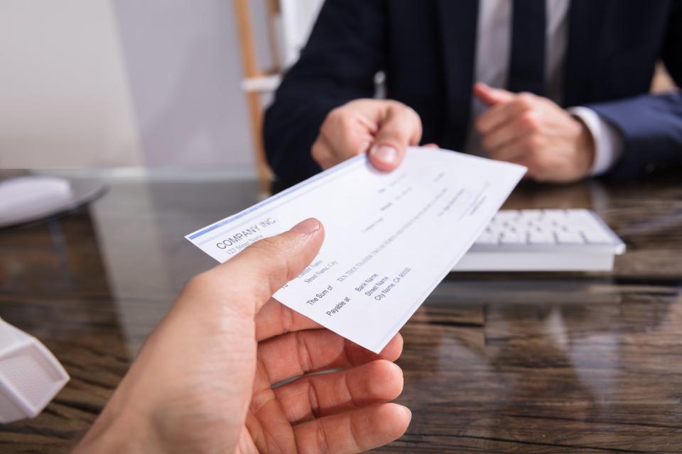 Man in suit handing over a paycheck