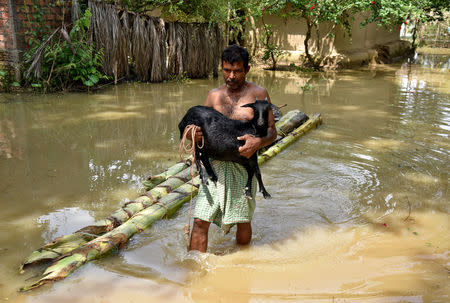 A man carries his goat as he wades through a flooded area at a village in Nagaon district, in the northeastern state of Assam, India, June 19, 2018. REUTERS/Anuwar Hazarika