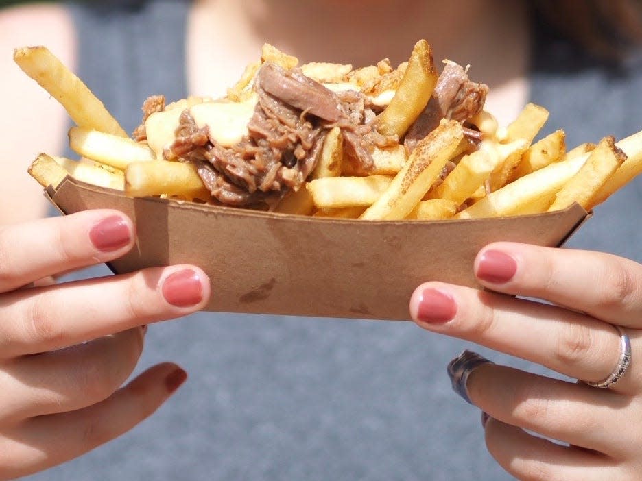 hands holding takeout boat of poutine from canada pavilion at epcot