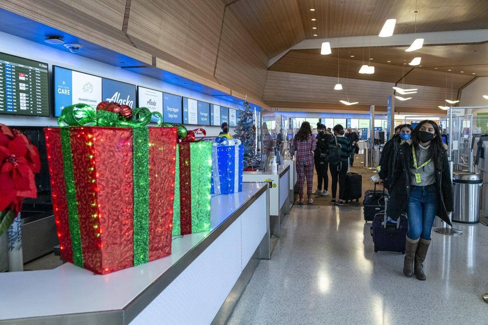 Travelers wearing protective masks walk to a security gate at San Francisco International Airport (SFO) in San Francisco, California, U.S., on Monday, Dec. 21, 2020.