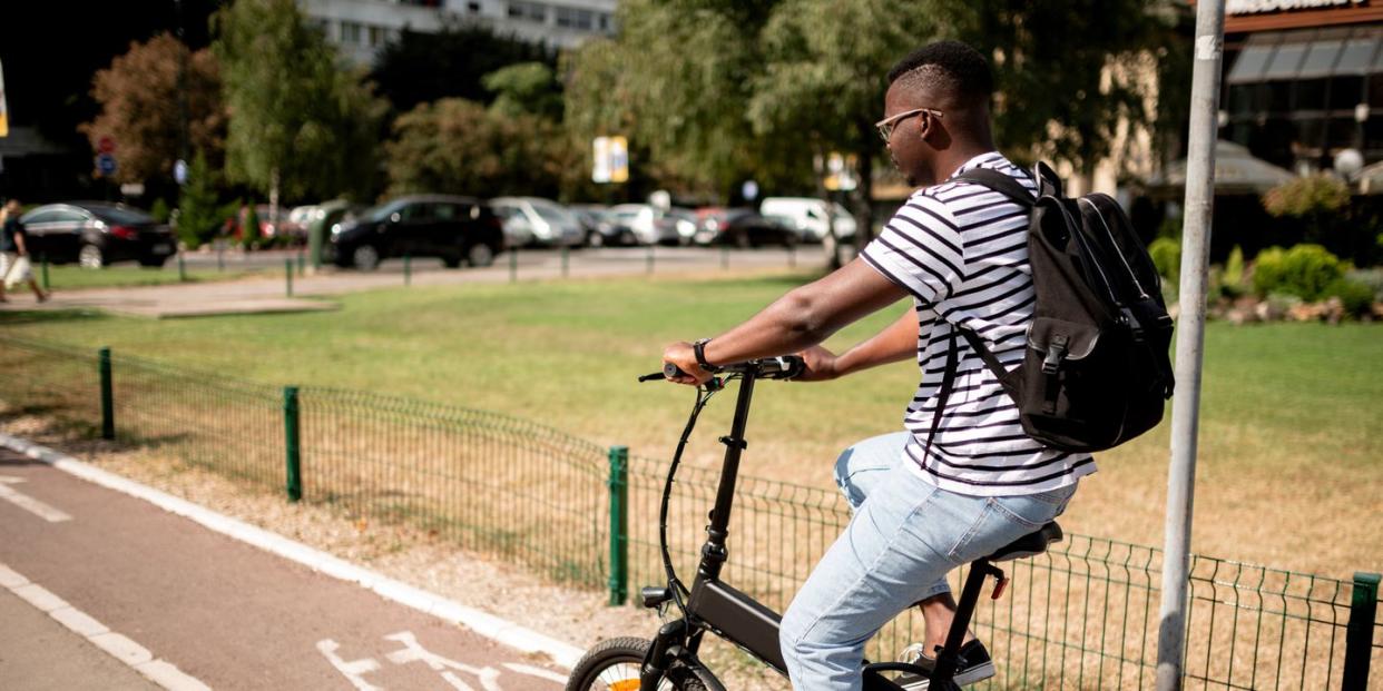 side view of a young african american male student riding a bicycle