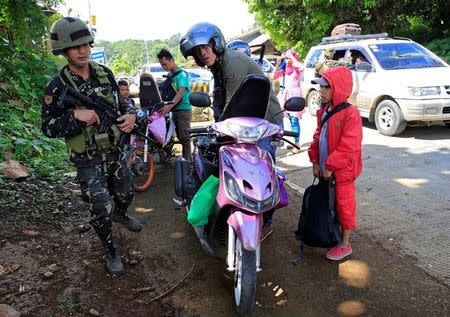 A government soldier inspects a motorcycle driver at a checkpoint along a main highway in Pantar town, Lanao del Norte, after residents started to evacuate their hometown of Marawi city, southern Philippines May 24, 2017. REUTERS/Romeo Ranoco