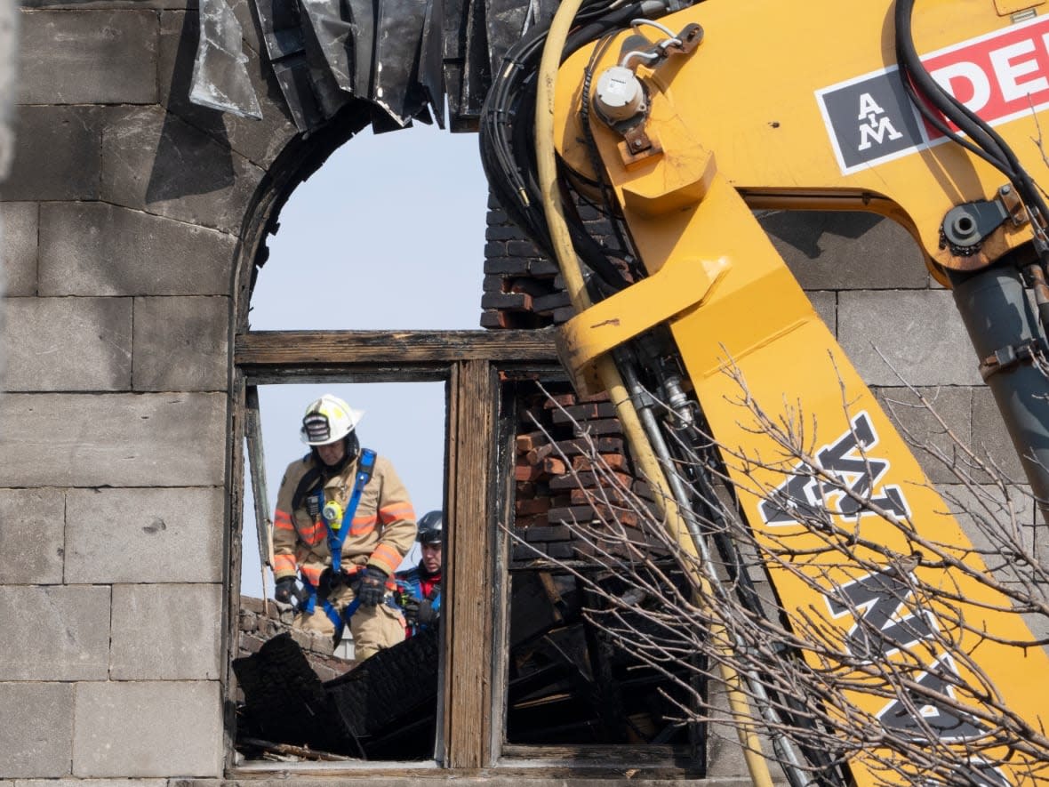 Firefighters are seen searching the building where a fire broke out last Thursday, leaving destruction and tragedy in its wake.  (Ryan Remiorz/The Canadian Press - image credit)