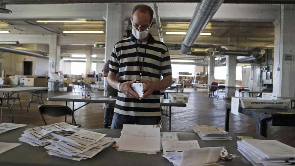 Mike Babinski opens applications for voter ballots at the Cuyahoga County Board of Elections Tuesday, July 14, 2020, in Cleveland. As more states embrace mail-in balloting, an often overlooked detail has emerged as a partisan dividing line: postage. Questions over whether postage will be required for absentee ballot applications and ballots themselves, who pays for it and what happen to envelopes without stamps are the subject of lawsuits and Statehouse political brawls. (AP Photo/Tony Dejak)