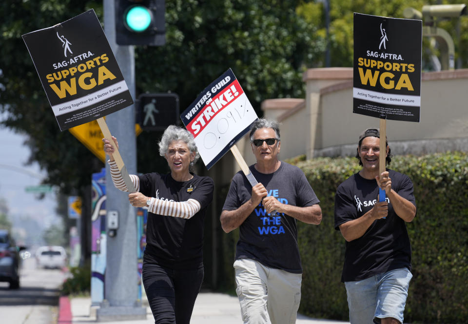 Actors Amy Aquino, left, and Michael Kajganich, right, join writer Steve Skrovan in a Writers Guild rally outside Warner Bros. Studios, Monday, May 22, 2023, in Burbank, Calif. (AP Photo/Chris Pizzello)