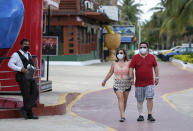 Tourists walk past restaurants and shops along an empty sidewalk in Cancun, Mexico, Saturday, June 13, 2020. In Quintana Roo state, where Cancun is located, tourism is the only industry there is, and Cancun is the only major Mexican resort to reopen so far. (AP Photo/Victor Ruiz)