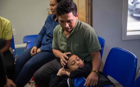 An immigrant from El Salvador and his 10-year-old son rest after being released from detention in McAllen, Texas - Credit:  LOREN ELLIOTT/AFP