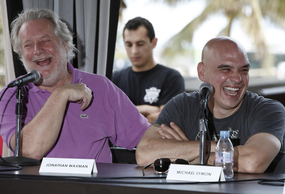 Celebrity chefs Jonathan Waxman, left, and Michael Symon laugh during a panel discussion about the experience of competing on TV cooking competitions, Saturday, Feb. 25, 2012 in Miami. (AP Photo/Carlo Allegri)