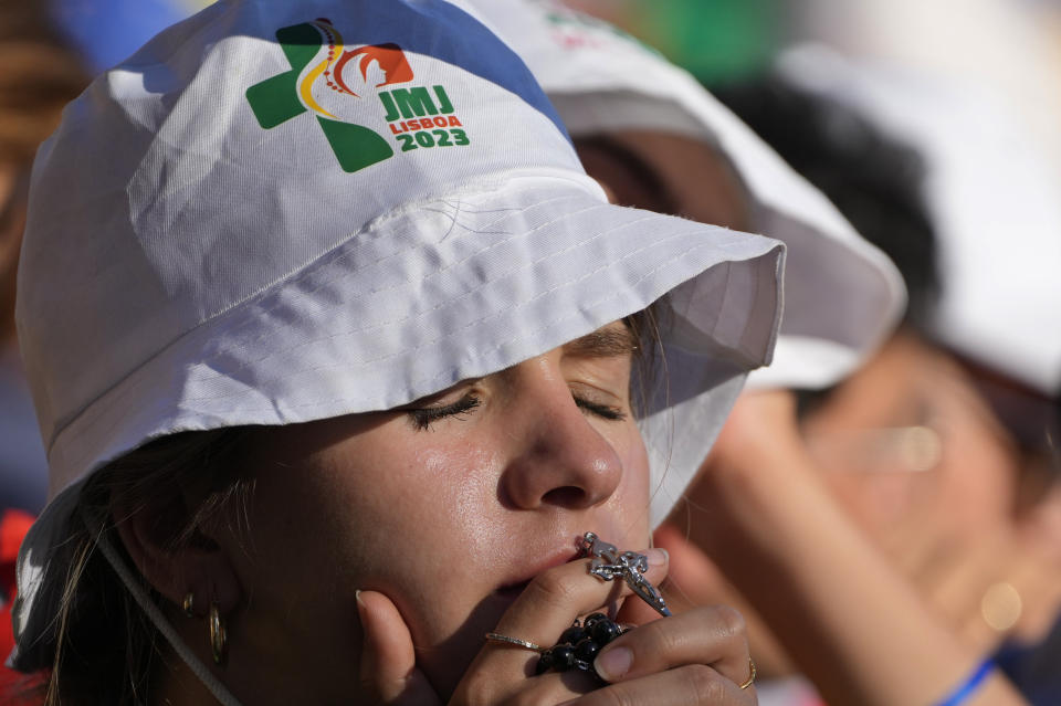 A pilgrim kisses a crucifix while Pope Francis presides over a via crucis (Way of the Cross) at the Eduardo VII Park with young people in Lisbon, Friday, Aug. 4, 2023. Pope Francis is on the third day of a five-day pastoral visit to Portugal that includes the participation at the 37th World Youth Day, and a pilgrimage to the holy shrine of Fatima. (AP Photo/Gregorio Borgia)