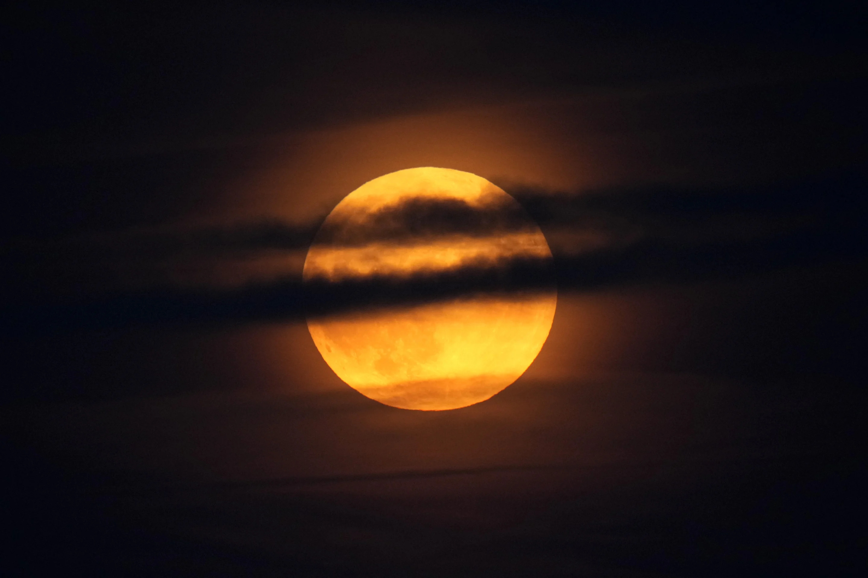 The moon rises through clouds over the Atlantic Ocean off the coast of Camden, Maine, on Tuesday.