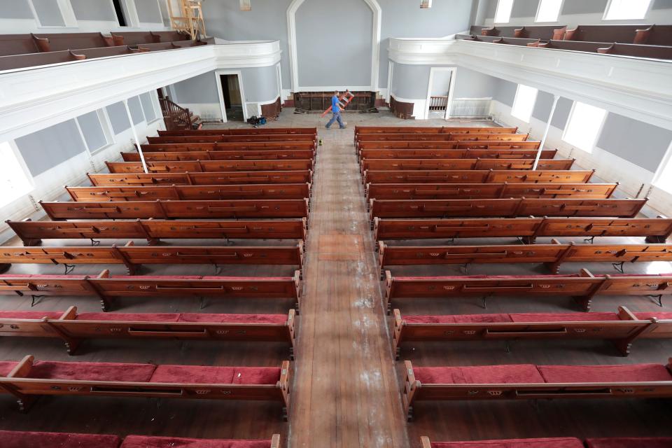 In this file photo, Matt Faria, of Encore Fire Protection makes his way past the iconic pews of the First Baptist Church in New Bedford as he installs a new sprinkler system in the historic building. The old church is being converted into the Steeple Playhouse and home to Your Theatre.