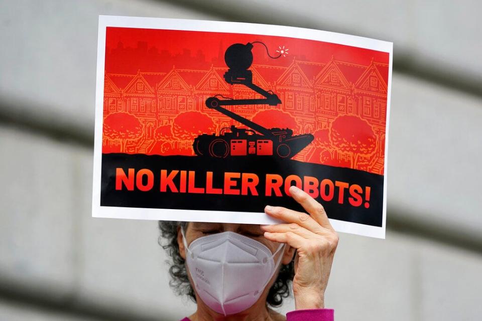 A woman holds a sign while taking part in a demonstration about the use of robots by the San Francisco Police Department outside of City Hall on Dec. 5, 2022.