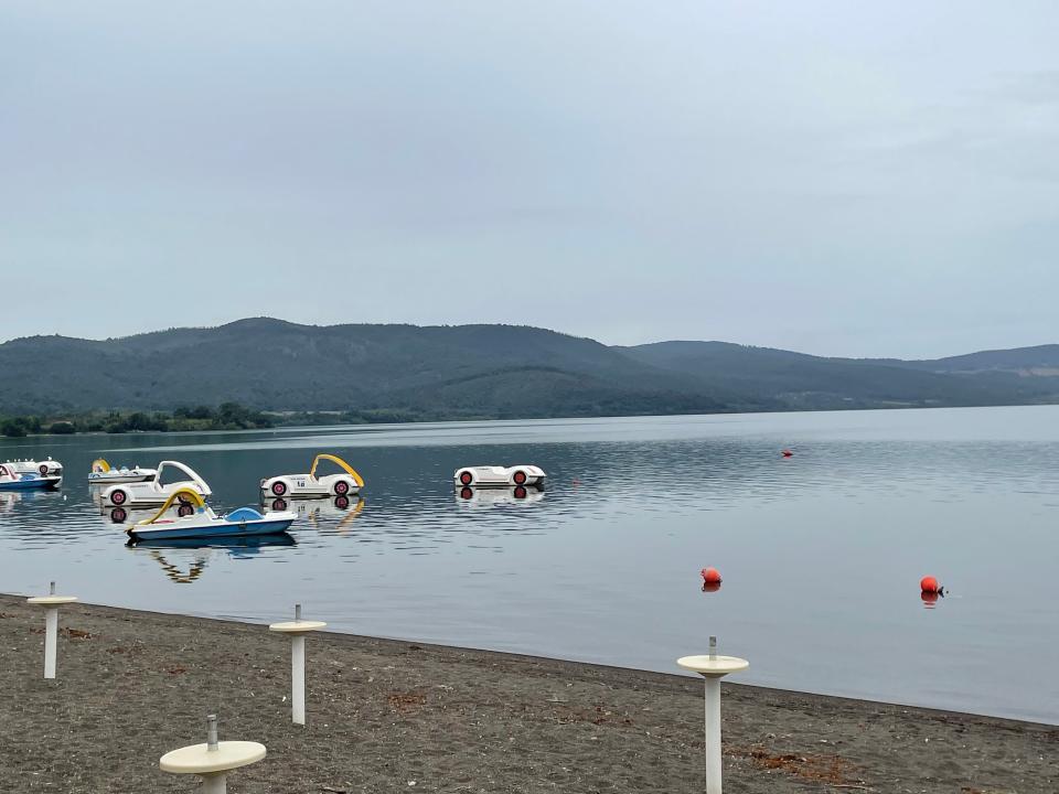 Bracciano Lake with paddle boats and floatation devices in the water. The sky is gray and overcast