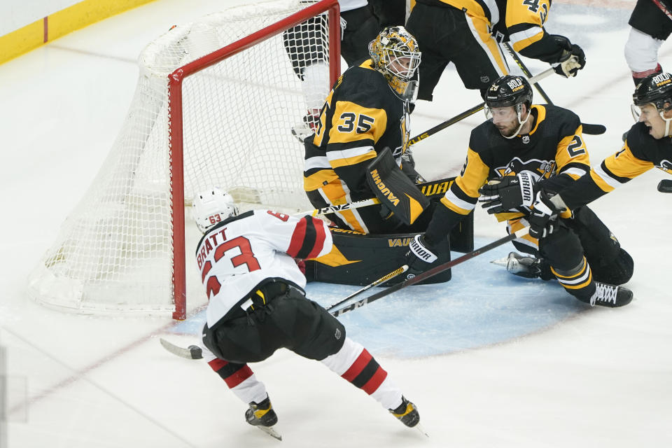 New Jersey Devils' Jesper Bratt, left, scores has first goal during the first period against goaltender Tristan Jarry (35) in an NHL hockey game, Thursday, Feb. 24, 2022, in Pittsburgh. (AP Photo/Keith Srakocic)