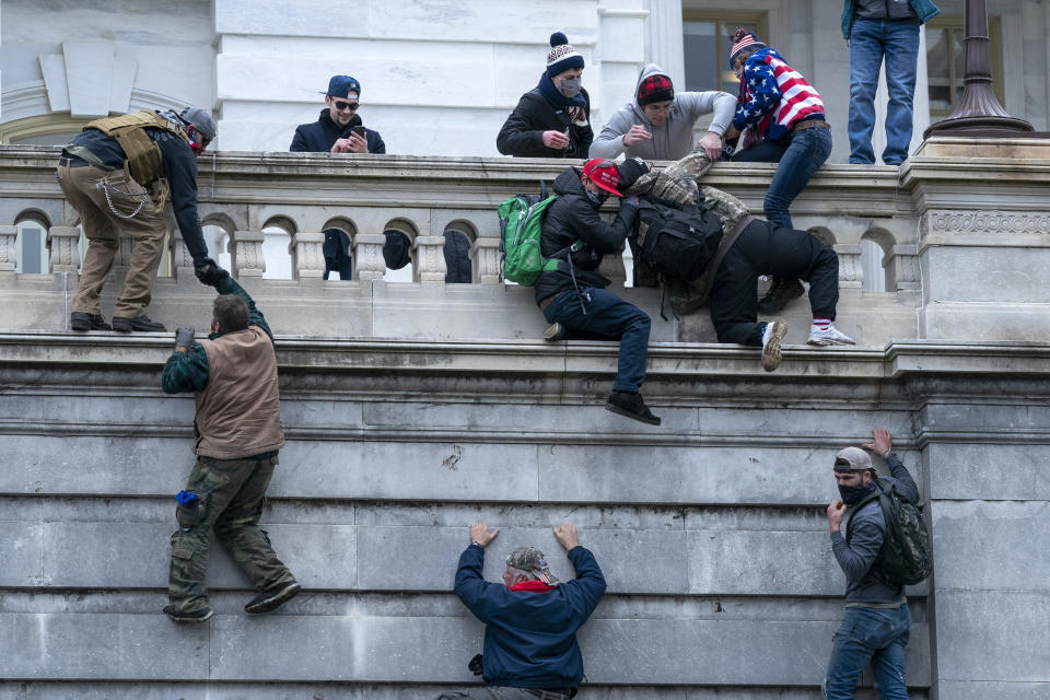 FILE - Insurrections loyal to President Donald Trump climb the west wall of the the U.S. Capitol, Jan. 6, 2021, in Washington. A federal judge has refused to throw out a key charge against two men accused of storming the U.S. Capitol to obstruct Congress from certifying President Joe Biden's electoral victory. U.S. District Judge Dabney Friedrich ruled on Friday that an obstruction charge applies to the Justice Department’s case against Ronald Sandlin and Nathaniel DeGrave. (AP Photo/Jose Luis Magana, File)