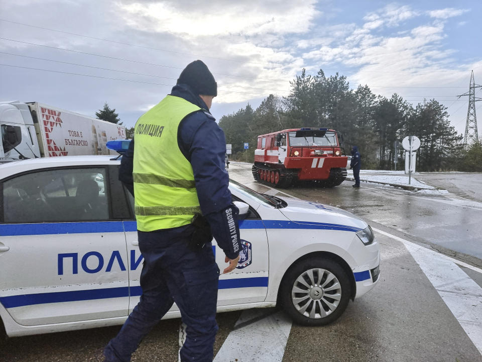 Policeman and civil service vehicle seen regulate the traffic on the road near town of Dobrich, Bulgaria, Sunday, Nov. 19 2023. Gale-force winds and heavy rain and snow hit large parts of Bulgaria claiming the lives of two people and causing severe damages and disrupting power supply in towns and villages, officials said on Sunday. (Bulgarian News Agency via AP)