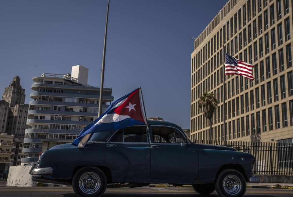 Un automóvil estadounidense clásico con bandera cubana pasa frente a la embajada estadounidense durante un mitin que pide el fin del embargo de Estados Unidos contra la nación isleña, en La Habana, Cuba, el domingo 28 de marzo de 2021. (Foto AP/Ramón Espinosa).