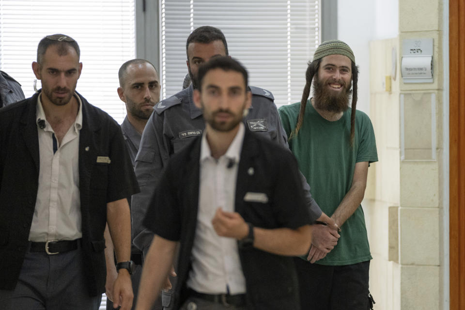 Elisha Yered, 22, right, is led handcuffed by officers during an appearance at the Jerusalem District Court on Tuesday, Aug. 8, 2023. Yered is one of two Israeli settlers arrested on suspicion of involvement in the killing of a Palestinian man in the West Bank on Friday. (AP Photo/Ohad Zwigenberg)