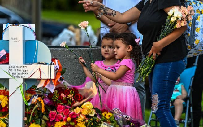 Audrey and Aubrey Ramirez lay flowers at a makeshift memorial outside the Uvalde County Courthouse in Uvalde, Texas on May 27. (Chandan/KhannaGetty Images)