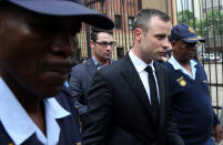 Oscar Pistorius, middle, accompanied by brother Carl Pistorius, behind, and police officers leaves the high court in Pretoria, South Africa, Wednesday, April 16, 2014. Pistorius is charged with murder for the shooting death of his girlfriend, Reeva Steenkamp, on Valentines Day in 2013. (AP Photo/Themba Hadebe)