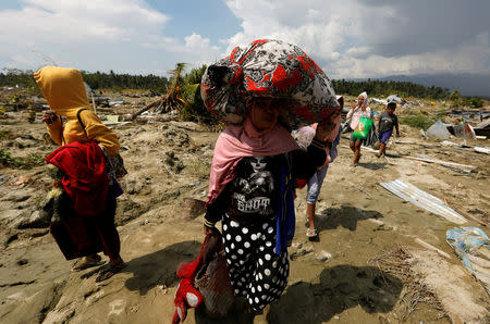 Villagers carry their belonging as they walk through mud near the ruins of houses after an earthquake hit Jono Oge village in Sigi, Indonesia's Sulawesi island, October 3, 2018. REUTERS/Beawiharta