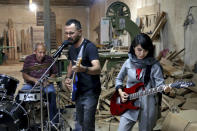 In this July 20, 2018 photo, members of the rock band Arikayn, Afghan musicians Hakim Ebrahimi, center, and Soraya Hosseini, right, play with Kourosh Ghasemi, an Iranian drummer, at a furniture workshop in Eslamshahr, on the outskirts of Iran’s capital, Tehran. The band, made up of Afghan migrants, plays Metallica-inspired ballads about the struggles of millions of Afghans who have fled to Iran to escape decades of war and unrest. In Iran they face discrimination, and have had to contend with hard-liners opposed to Western culture. (AP Photo/Ebrahim Noroozi)