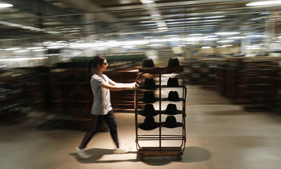 A woman worker pushes a cart with hats in Borsalino's hat factory, in Spinetta Marengo, near Alessandria, Italy, Thursday, Jan. 17, 2019. Borsalino's prized felt hats are handmade by 80 workers in its Piemonte factory, many who have worked there for decades, with original machinery that use hot water and steam to transform rabbit fur into highly prized felt, that is formed into clochards, dyed and molded by hand to create the latest styles. (AP Photo/Antonio Calanni)