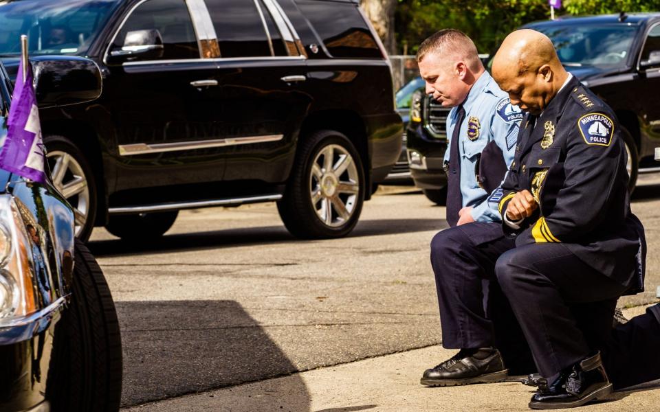 Minneapolis Police Chief Medaria Arradondo (R) kneels as the remains of George Floyd are taken to a memorial service in his honor on June 4, 2020 -  KEREM YUCEL/AFP