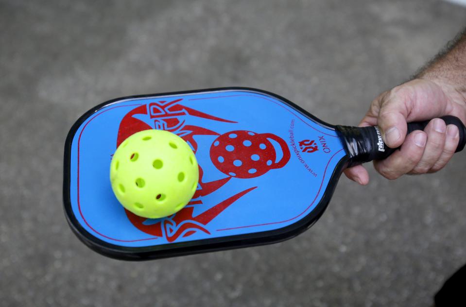 Rich Miller, of Massillon, shows the paddle and ball used for outdoor pickleball. Miller, who is hooked on the sport converted a basketball court at Lincoln Park into a pickleball court.