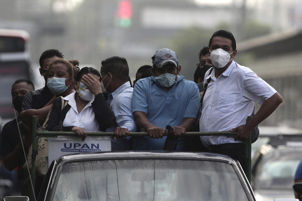 Commuters, wearing protective face masks, travel in the bed of a truck as public transportation has been temporarily suspended by the government in an effort to contain the spread of the new coronavirus, in San Salvador, El Salvador, Friday, Aug. 7, 2020. For months, the strictest measures confronting the COVID-19 pandemic in Latin America seemed to keep infections in check in El Salvador, but a gradual reopening combined with a political stalemate has seen infections increase nearly fourfold. (AP Photo/Salvador Melendez)