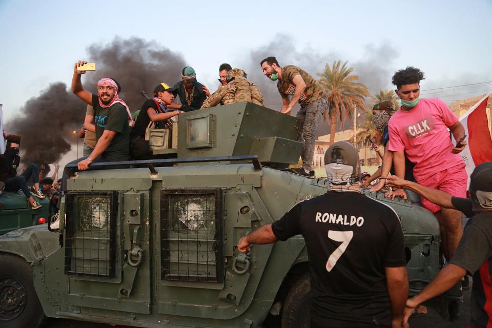 Anti-government protesters confront a soldier from the Federal Police Rapid Response Forces before they burn the armored vehicle, during a demonstration in Baghdad, Iraq, Thursday, Oct. 3, 2019. Iraqi security forces fired live bullets into the air and used tear gas against a few hundred protesters in central Baghdad on Thursday, hours after a curfew was announced in the Iraqi capital on the heels of two days of deadly violence that gripped the country amid anti-government protests that killed over 19 people in two days. (AP Photo/Hadi Mizban)