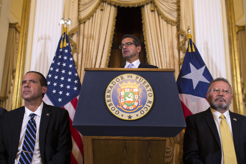 Pedro Pierluisi, sworn in as Puerto Rico's governor, speaks during a press conference, in San Juan, Puerto Rico, Friday, Aug. 2, 2019. Departing Puerto Rico Gov. Ricardo Rossello resigned as promised on Friday and swore in Pierluisi, a veteran politician as his replacement, a move certain to throw the U.S. territory into a period of political chaos that will be fought out in court. Pierluisi is flanked by lawmakers Jorge Navarro, left and Jose Aponte. (AP Photo/Dennis M. Rivera Pichardo)