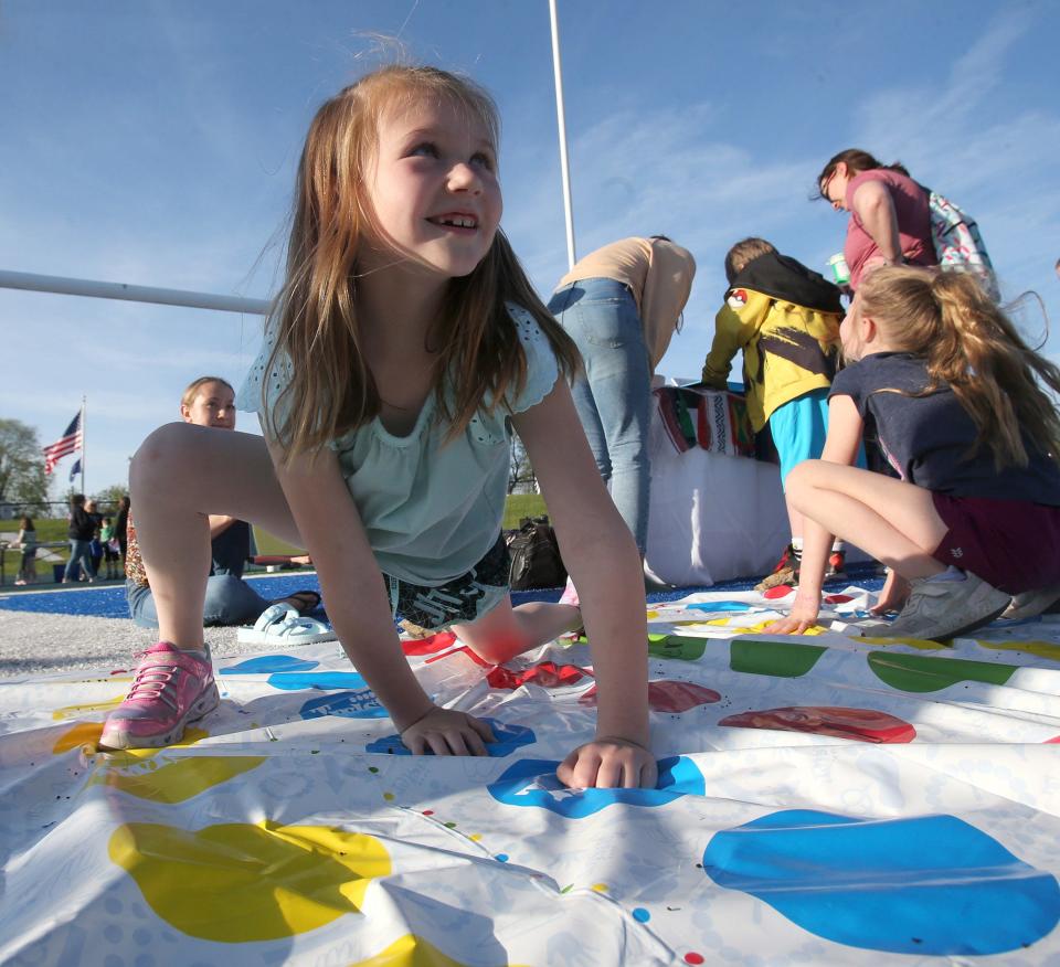 Finley Nisly plays Spanish Twister on May 9 during Reading Under the Lights at Blue Streak Stadium in Lake Township. At right is Lily McLaughlin. The event promoted reading and took place on the football field.