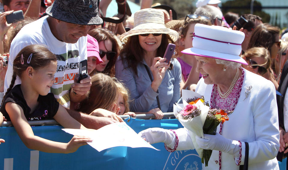 FILE - A young girl gives Queen Elizabeth II a picture she walks through the crowd at the Great Aussie Barbecue in Perth, Australia, Saturday, Oct. 29, 2011. After seven decades on the throne, Queen Elizabeth II is widely viewed in the U.K. as a rock in turbulent times. But in Britain’s former colonies, many see her as an anchor to an imperial past whose damage still lingers. (Michael O'Brien, Pool via AP, FIle)