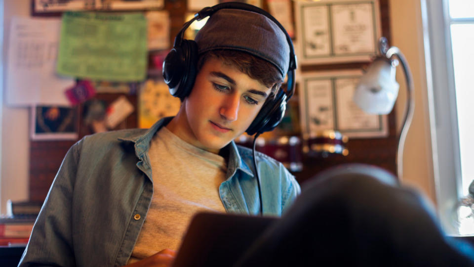 Teenager reading while wearing headphones