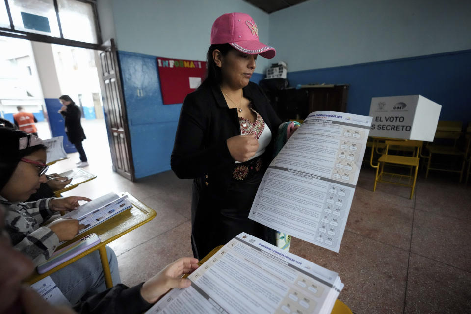 A woman holds the ballot to vote in a referendum proposed by President Daniel Noboa to endorse new security measures aimed at cracking down on criminal gangs fueling escalating violence, in Quito, Ecuador, Sunday, April 21, 2024. (AP Photo/Dolores Ochoa)