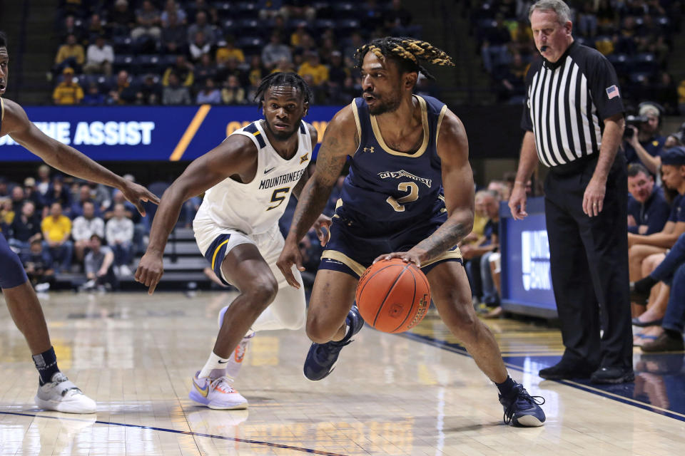 Mount St. Mary's guard Deandre Thomas (2) dribbles past West Virginia guard Joe Toussaint (5) during the first half of an NCAA college basketball game in Morgantown, W.Va., Monday, Nov. 7, 2022. (AP Photo/Kathleen Batten)