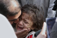 A man comforts a girl who lost her father in Monday's suicide bombing as they take part in a march denouncing militant attacks and demanding peace in the country in Peshawar, Pakistan, Wednesday, Feb. 1, 2023. (AP Photo/Muhammad Sajjad)