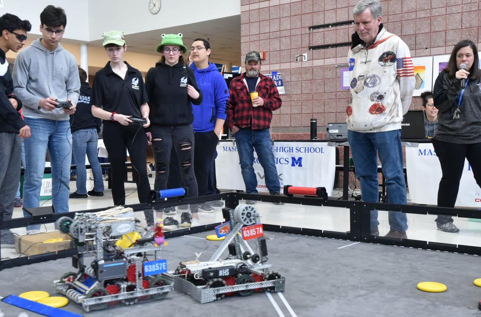 Jamie Hughes, center, works the controller as teammate Katrina Hughes watches as their robot works the ring on Saturday during an early match at Mashpee Middle-High School, which hosted a regional robotics competition.