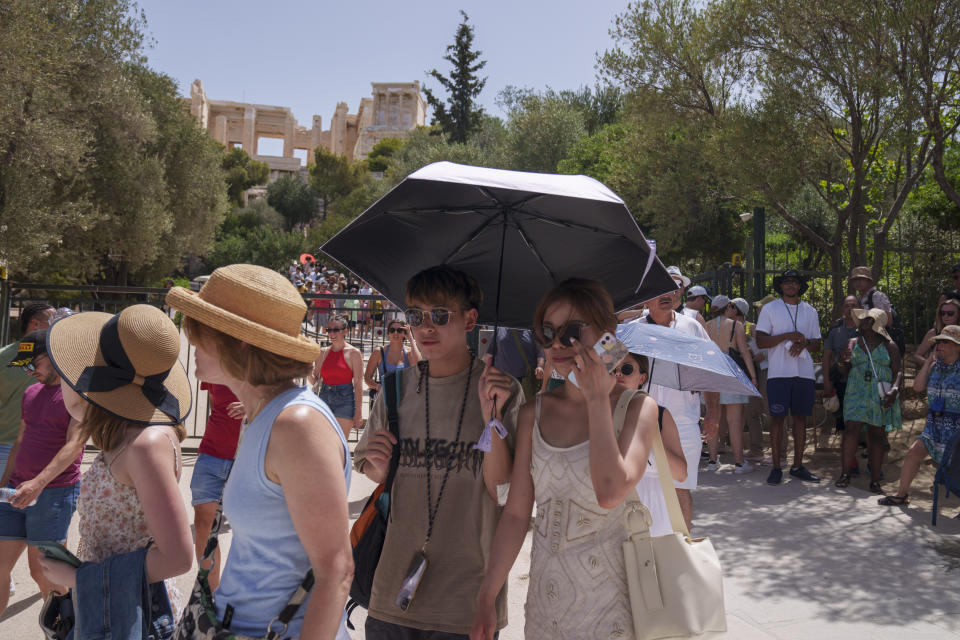 Tourists exit the ancient Acropolis in central Athens on Wednesday, June 12, 2024. The ancient site was closed to the public for five hours due to a heat wave that pushed temperatures to 39 degrees Celsius (102 Fahrenheit) in the capital and even higher in parts of central Greece. (AP Photo/Petros Giannakouris)