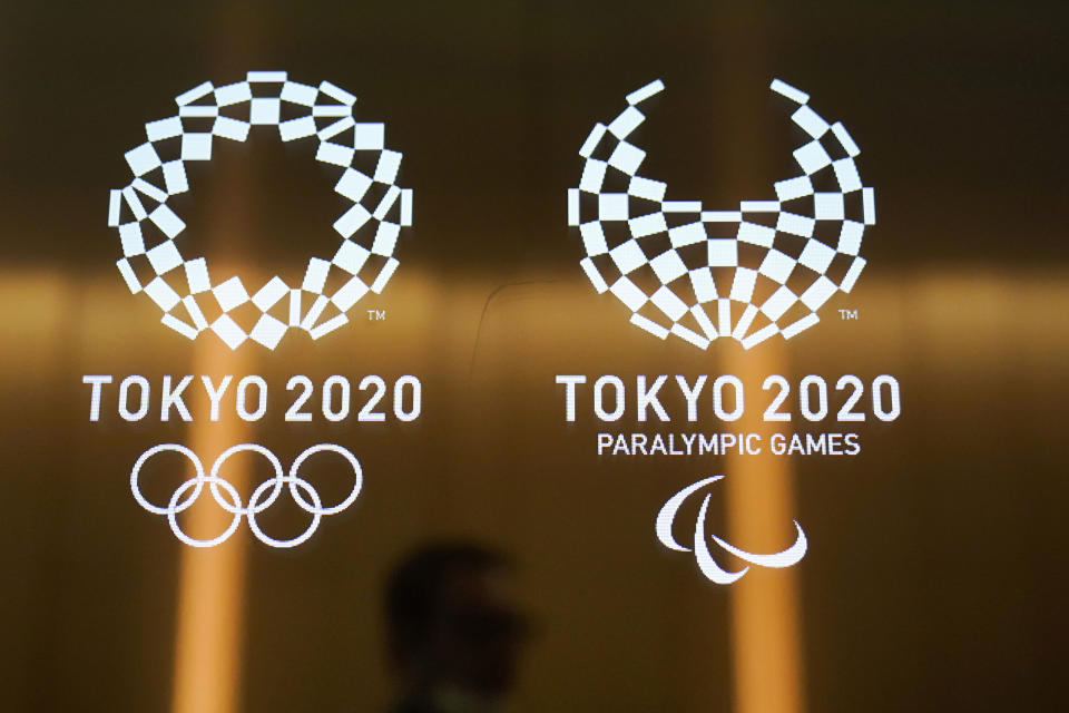 ARCHIVO - En esta foto del 11 de junio de 2019, un hombre pasa frente a los logos de los Juegos Olímpicos y Parlímpicos de Tokio 2020. (AP Foto/Jae C. Hong, archivo)