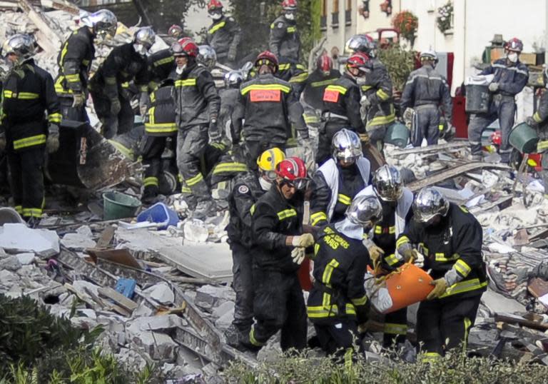 Firefighters carry a body found in the rubble of a four-storey residential building that collapsed following a blast in Rosny-sous-Bois in the eastern suburbs of Paris on August 31, 2014